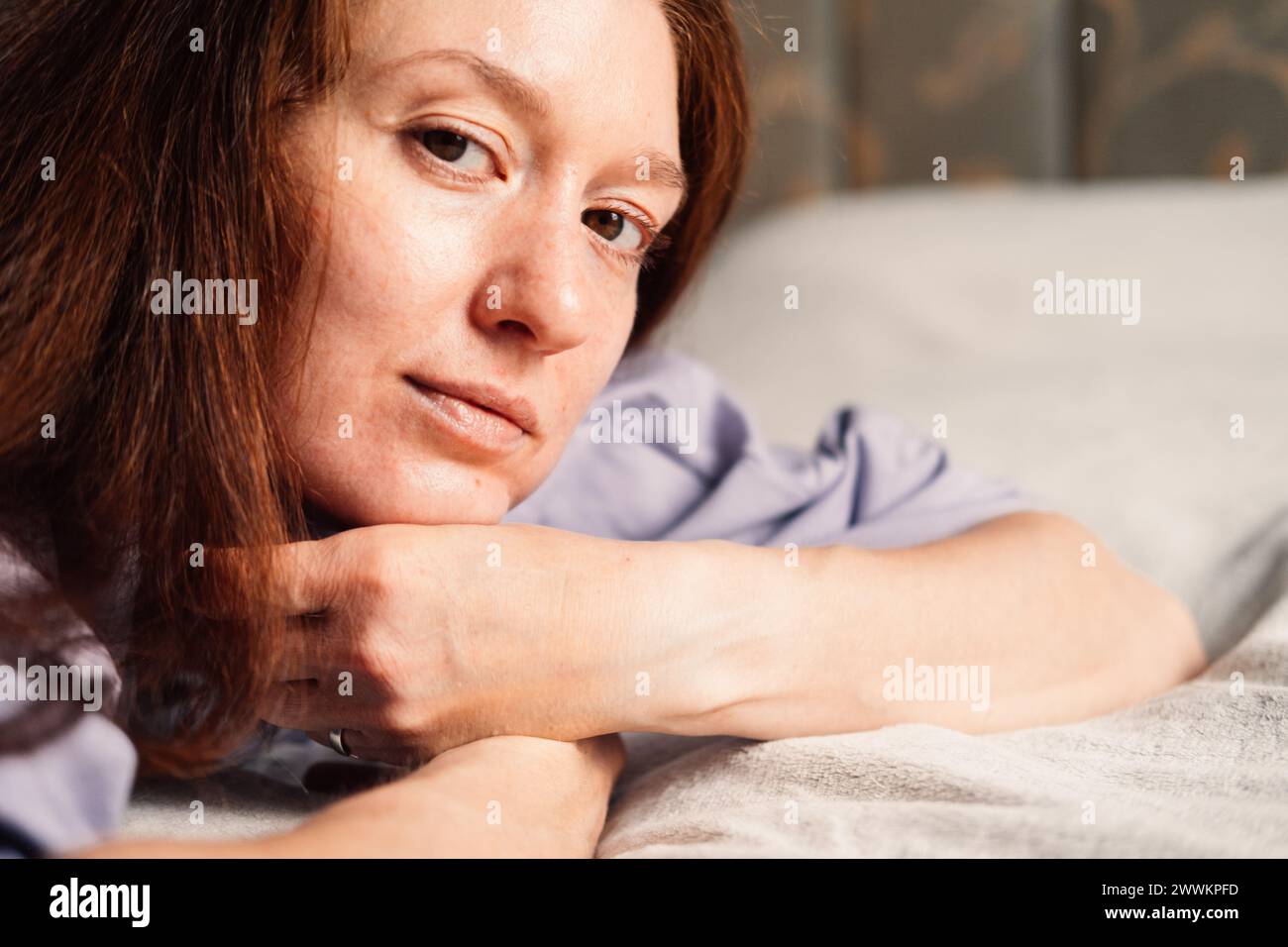 As morning light filters in, a woman lies in serene contemplation, embracing quietude of bedroom  Stock Photo