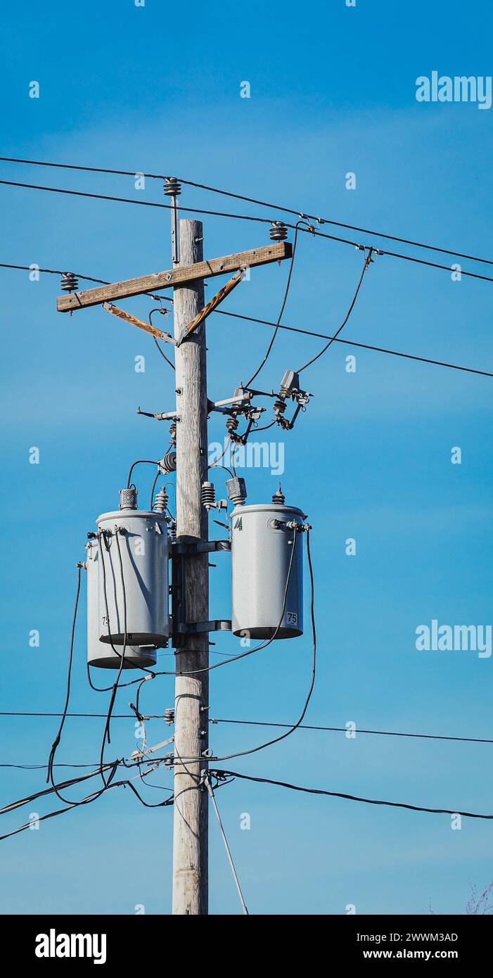A tall utility pole with overhead power lines and two hanging buckets Stock Photo