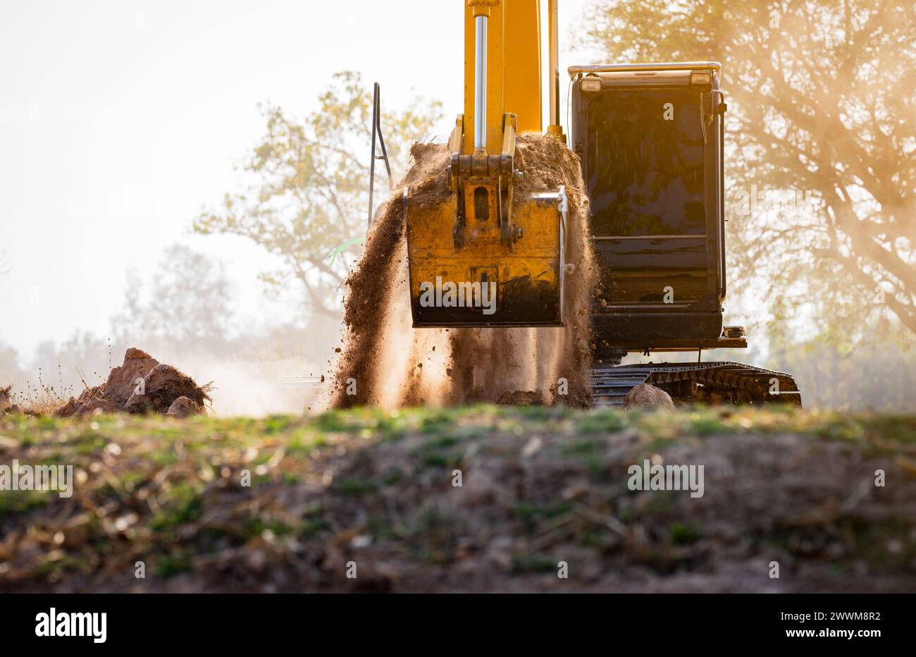 Backhoe working by digging soil at construction site.  Crawler excavator digging on demolition site. Excavating machine. Earth moving machine. Stock Photo