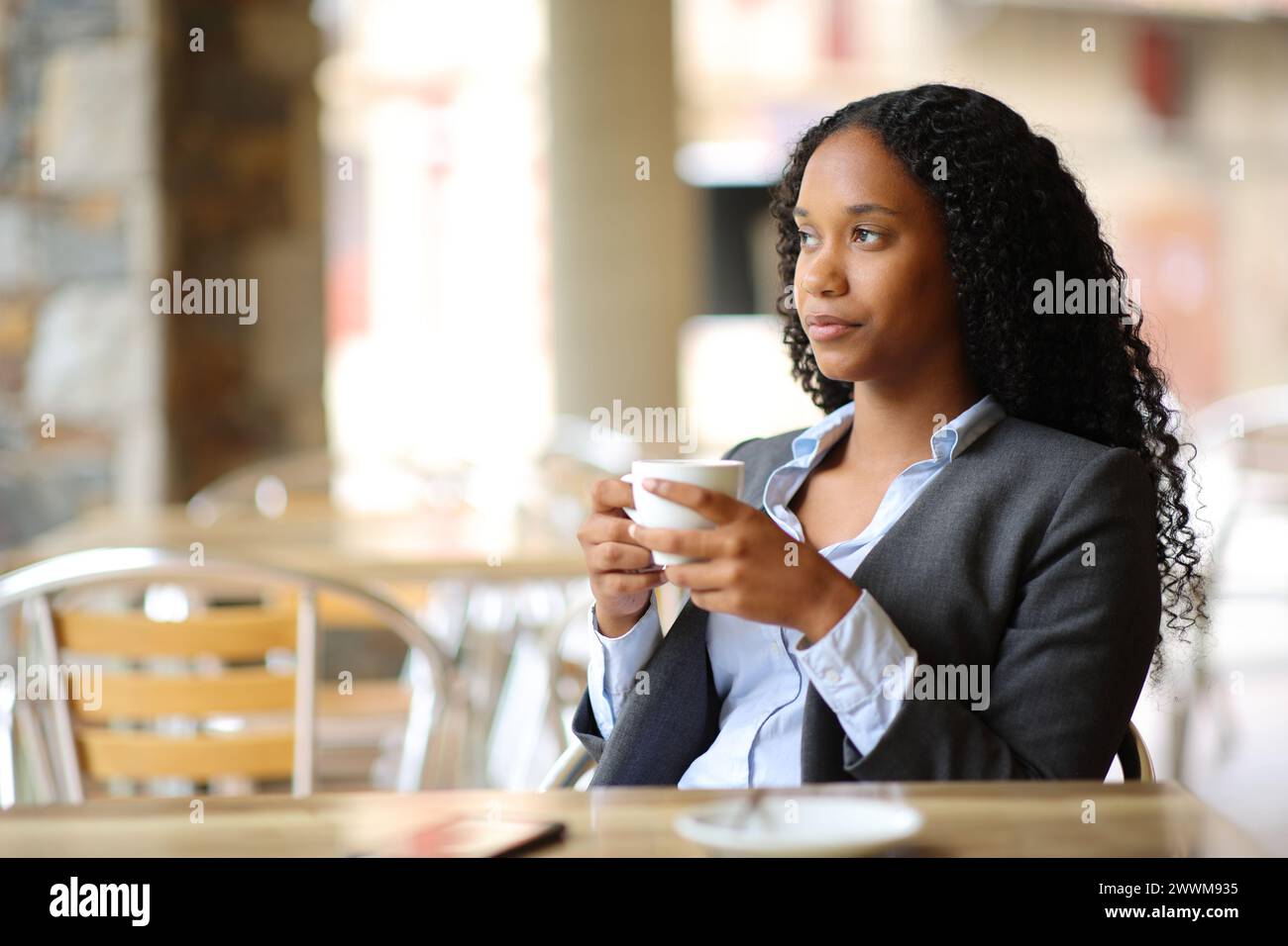 Relaxed black executive drinking coffee contemplating in a restaurant terrace Stock Photo