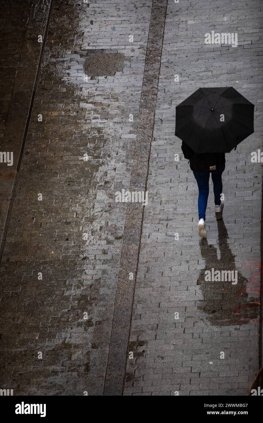 Aerial view of a person walking with an umbrella on a rainy day Stock Photo