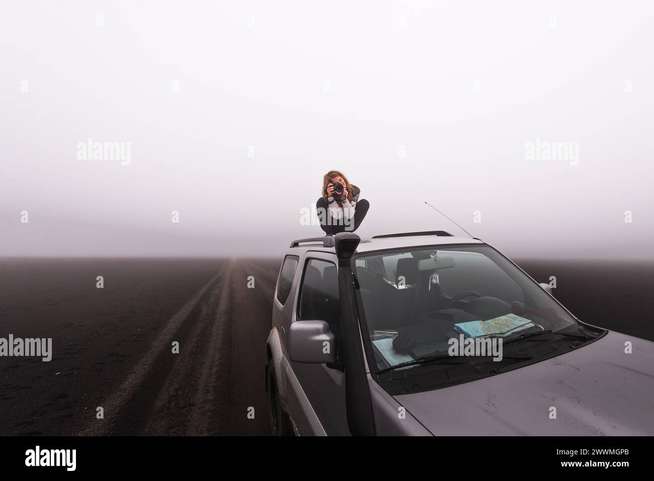 Woman standing on roof of car while taking pictures highlands iceland Stock Photo
