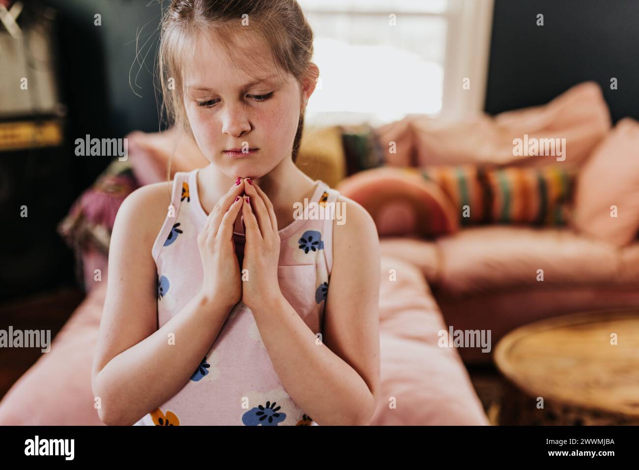 close up of young girl meditating in tree pose in living room Stock Photo