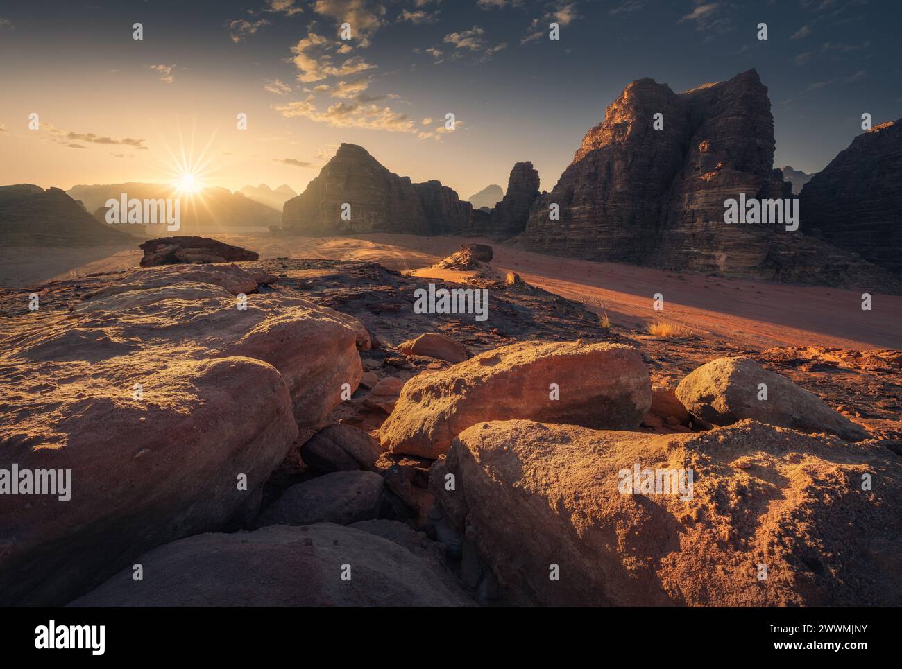 Breathtaking Sunrise over Red Sand and Towering Cliffs of Wadi Rum Stock Photo