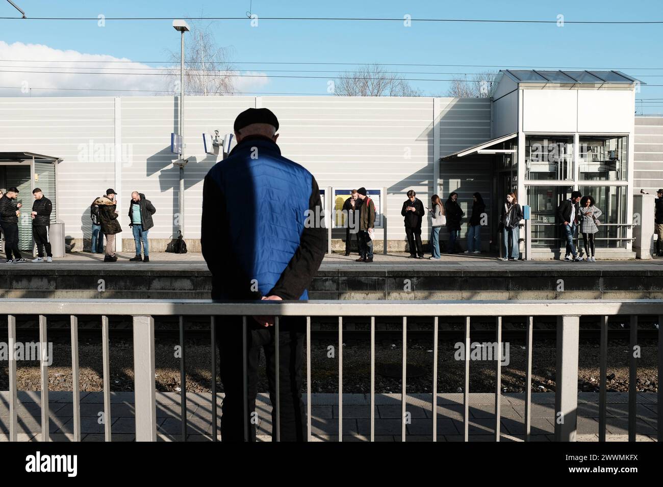 Wartende Personen auf Bahnsteig Wartende Personen auf Bahnsteig. Im Vordergrund ist ein äterer Herr in Rückenansicht mit Blick auf Gleise erkennbar, a Stock Photo