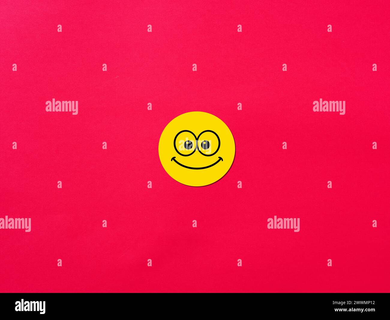 Smiling happy face emoticon on red background. Happiness, joy and positivity concepts. Stock Photo