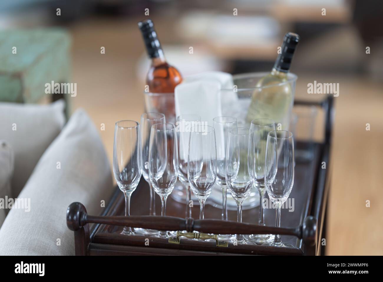 A tray of wine glasses and a bottle of wine. The tray is placed on a wooden surface Stock Photo
