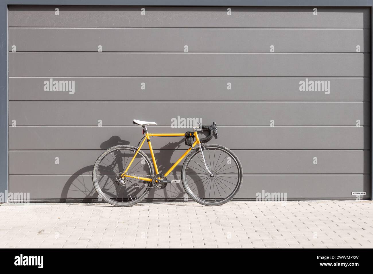 vintage yellow fixie road bike stacked on a gray wall Stock Photo