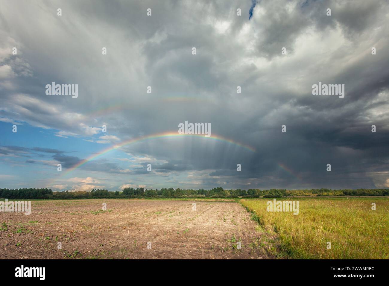 A rainbow in the cloudy sky over the fields, Nowiny, eastern Poland Stock Photo