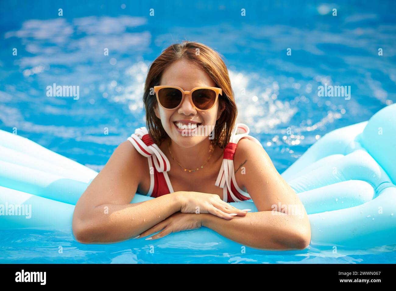 Happy woman in sunglasses spending time in swimming pool on sunny day Stock Photo
