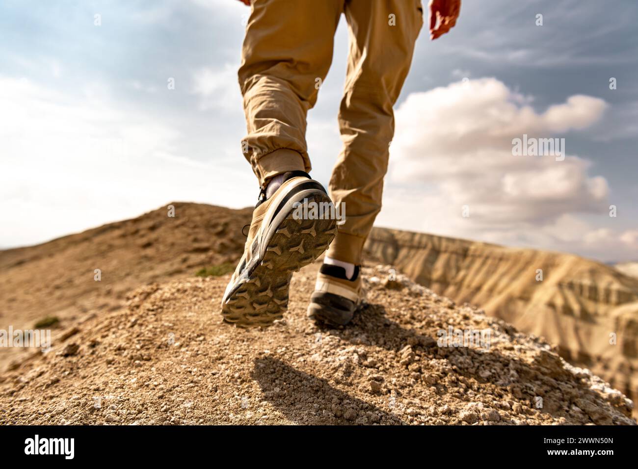 Close up photo of hiker legs and boots is walking uphill against blue sky Stock Photo