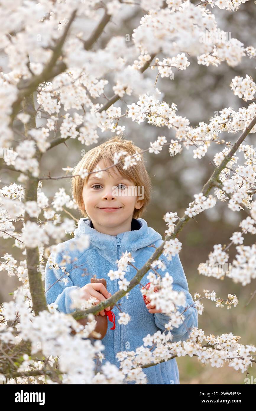 Beautiful blond child, boy, holding twig, braided whip made from pussy willow, traditional symbol of Czech Easter used for whipping girls and basket w Stock Photo