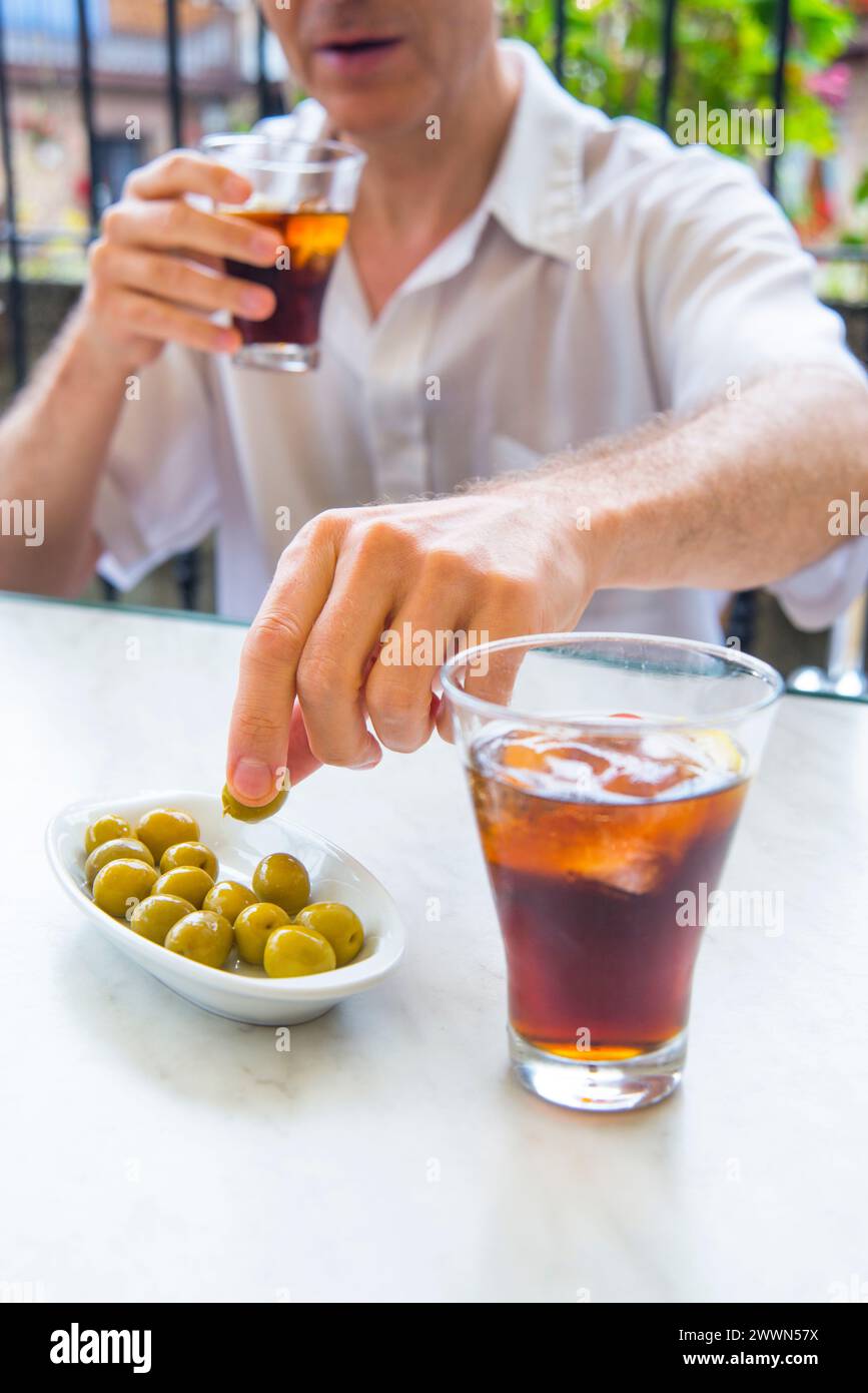 Man drinking vermouth and eating olives in a terrace. Stock Photo