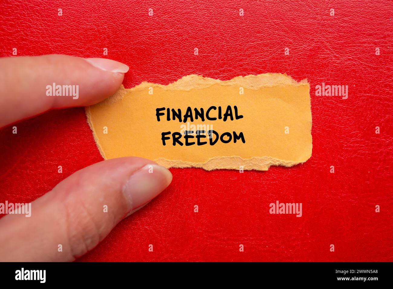 Financial freedom words written on orange torn paper piece with red ...