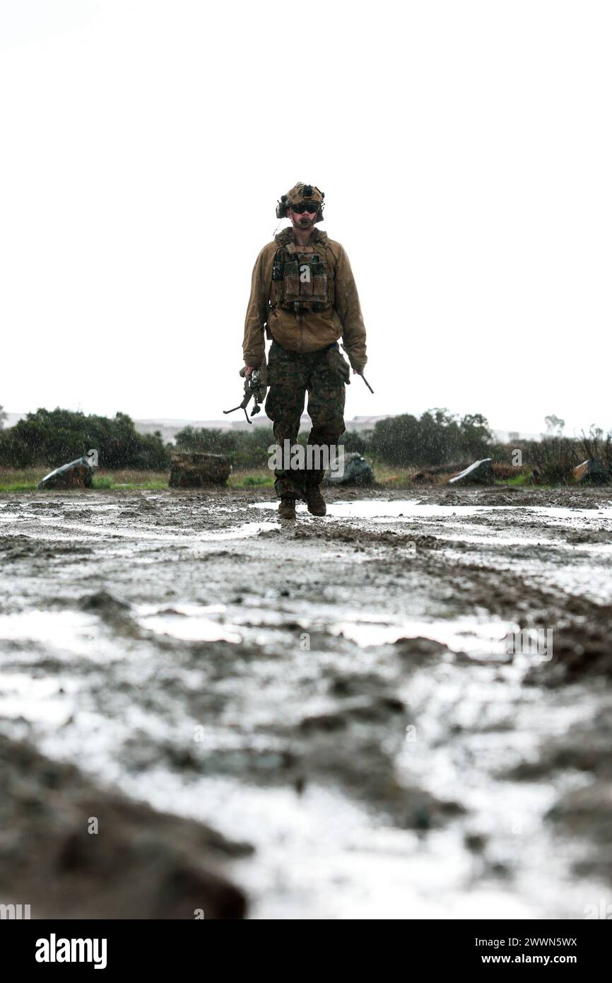 U.S. Marine Corps Cpl. Andrew Sweeney, a squad leader with Weapons Company, 2nd Battalion, 5th Marine Regiment, 1st Marine Division, walks to his squad during a tactical recovery of aircraft and personnel course hosted by Expeditionary Operations Training Group, I Marine Expeditionary Force, at Marine Corps Base Camp Pendleton, California, Feb. 7, 2024. The TRAP course is designed to develop the capabilities of Marines to recover aircraft, personnel and equipment in austere environments. EOTG is a section of the I MEF command element that trains and evaluates deploying Marine Expeditionary Uni Stock Photo