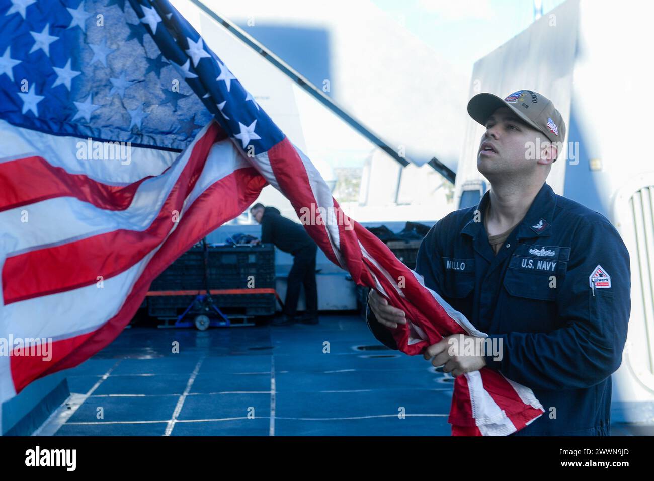 Quartermaster 3rd Class Andres Murillo, a native of Ponce, Puerto Rico, raises the national ensign on the weather decks aboard USS San Diego (LPD 22) while the ship gets underway for NASA’s Underway Recovery Test 11, Feb. 21, 2024. In preparation for NASA’s Artemis II crewed mission, which will send four astronauts in Orion beyond the Moon, NASA and the Department of Defense will conduct a series of tests to demonstrate and evaluate the processes, procedures and hardware used in recovery operations for crewed lunar missions. Amphibious transport docks, like USS San Diego, have unique capabilit Stock Photo