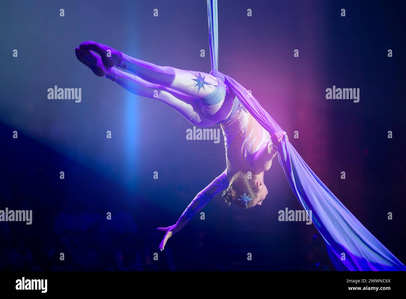 Performance by a circus acrobat artist. Girls perform aerial acrobatic elements on fabric. Stock Photo