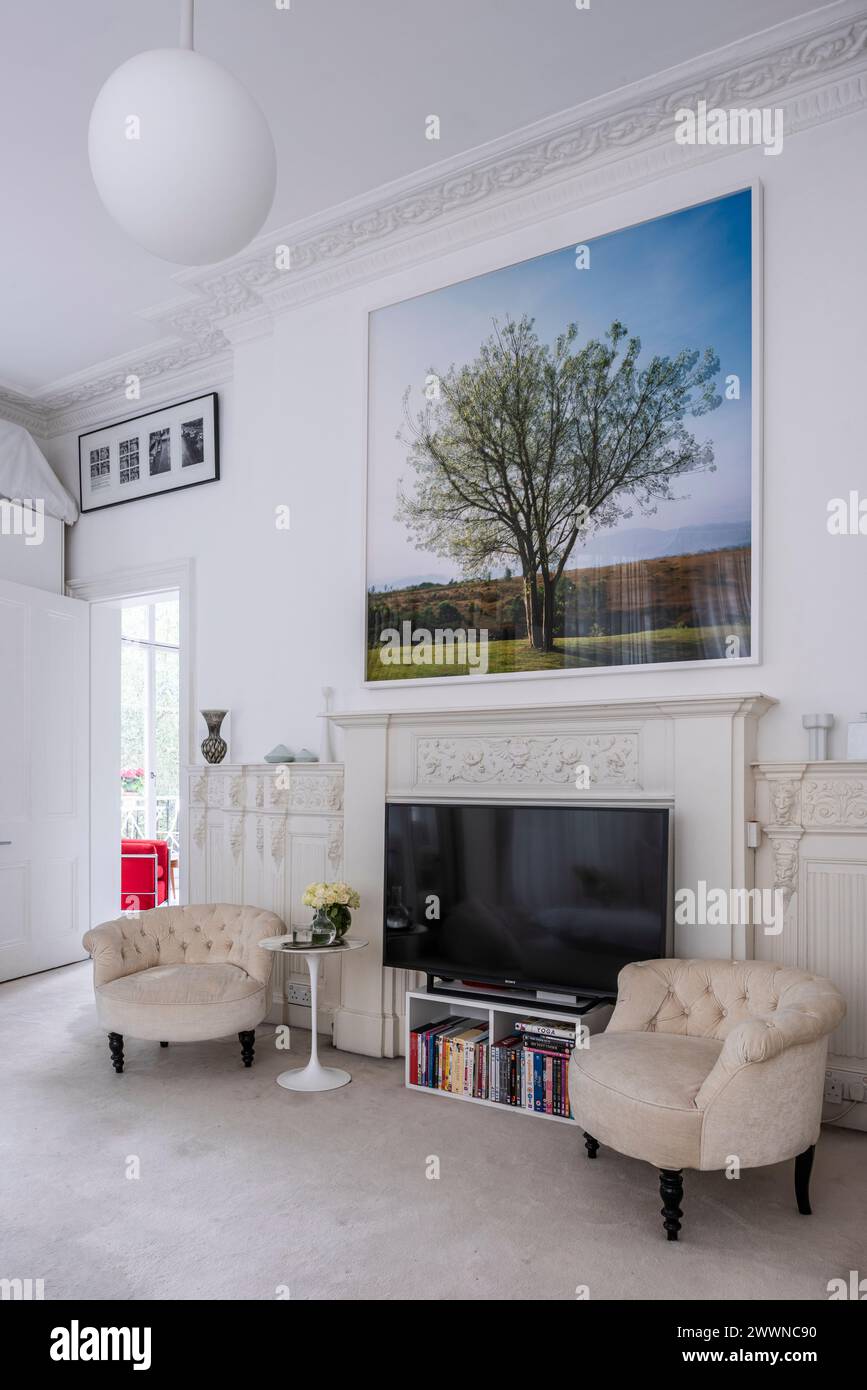 Pair of armchairs with TV and artwork in modern West London apartment, UK Stock Photo