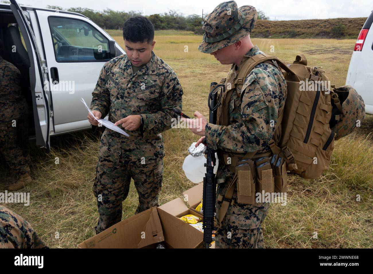 U.S. Marine Corps David Hernandez, a Network Administrator with Marine Aircraft Group (MAG) 24, 1st Marine Aircraft, shows a menu to a Marine on the rifle range during a volunteer event at Puuloa Range Training Facility, Ewa beach, Feb. 22, 2024. Marines with MAG-24 prepared and sold burgers, hotdogs, chips and drinks to Marines on the rifle range to raise funds for the 249th Marine Corps Ball.  Marine Corps Stock Photo