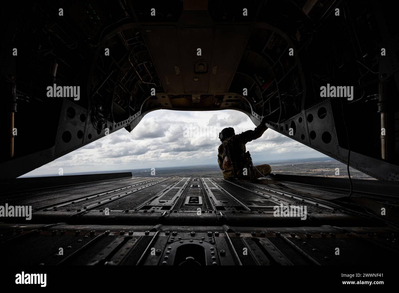 Alabama Army National Guard Sgt. Josh Market, a flight engineer assigned to Company B 1st Battalion, 169th Aviation Regiment, sits on the back of an ANG Ch-47F Chinook helicopter in the sky over Dannelly Field, Alabama, Feb. 9, 2024. The Chinook is an advanced multi-mission helicopter with advanced cargo-handling capabilities that complement the aircraft’s mission performance and handling characteristics.  Air Force Stock Photo