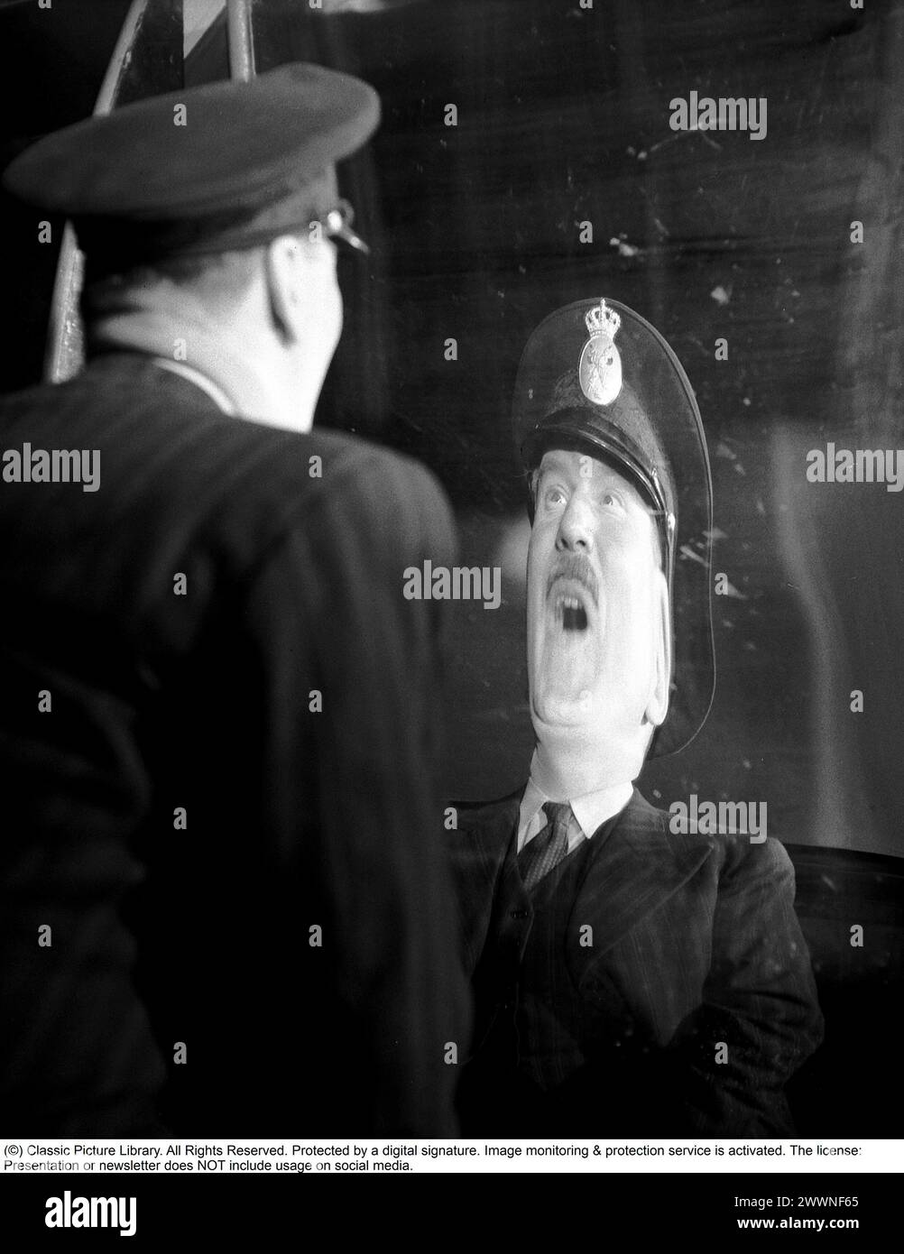 Laughing mirrors 1947. Actor Sigge Furst at the mirror attraction Skrattkammaren at the amusement park Gröna Lund, where he sees himself in a laughing mirror. Ordinary mirrors have a flat surface, while the mirrors at an amusement park could be curved both inwards and outwards, concave and convex. One mirror makes one look tall and thin. Others mirror short and thick. 1947. Kristoffersson ref AE45-12 Stock Photo
