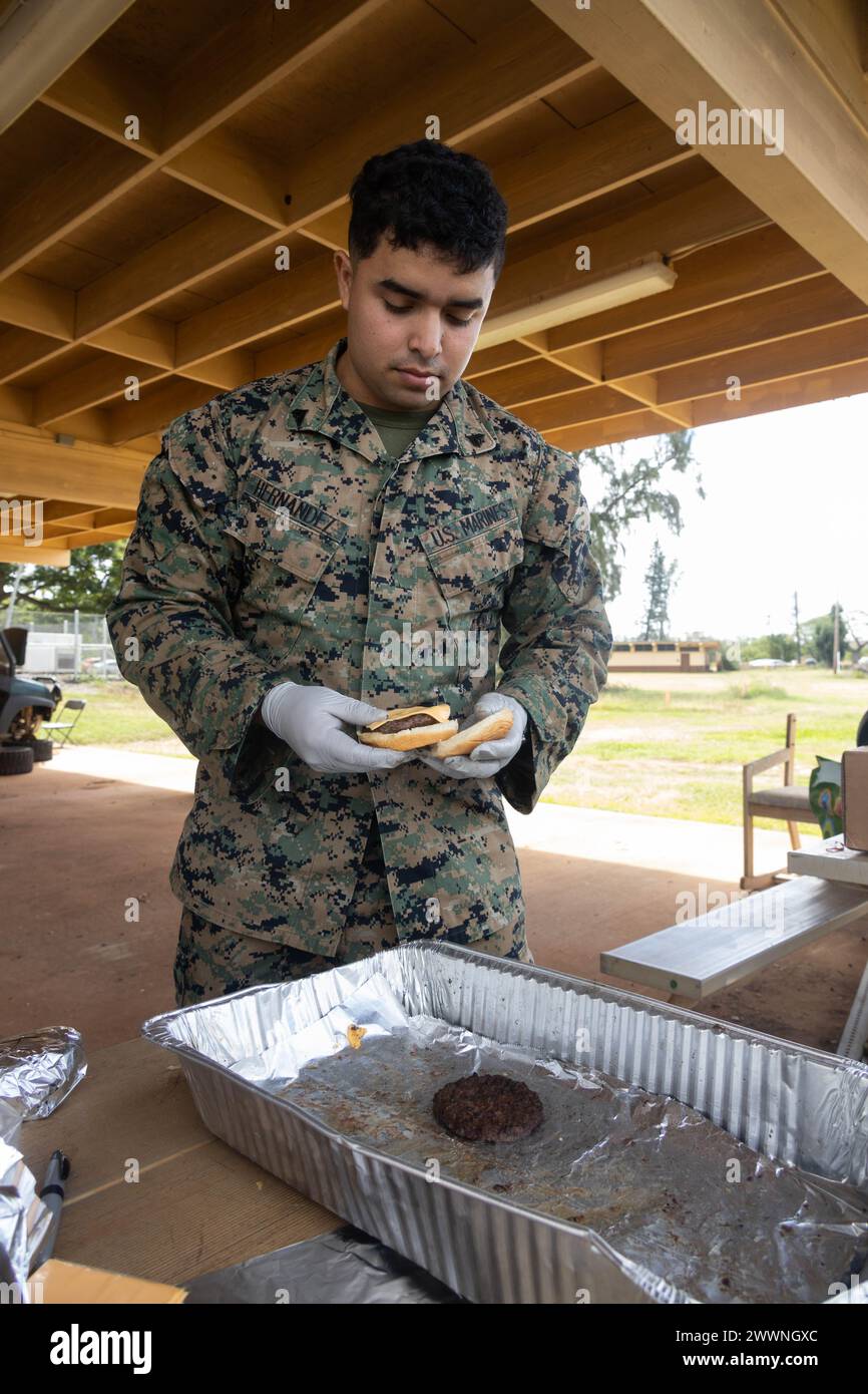 U.S. Marine Corps Cpl. David Hernandez, a Network Administrator with Marine Aircraft Group (MAG) 24, 1st Marine Aircraft Wing prepares a burger during a volunteer event at Puuloa Range Training Facility, Ewa Beach, Feb. 22, 2024. Marines with MAG-24 prepared and sold burgers and hotdogs to Marines on the rifle range to raise funds for the 249th Marine Corps Ball.  Marine Corps Stock Photo