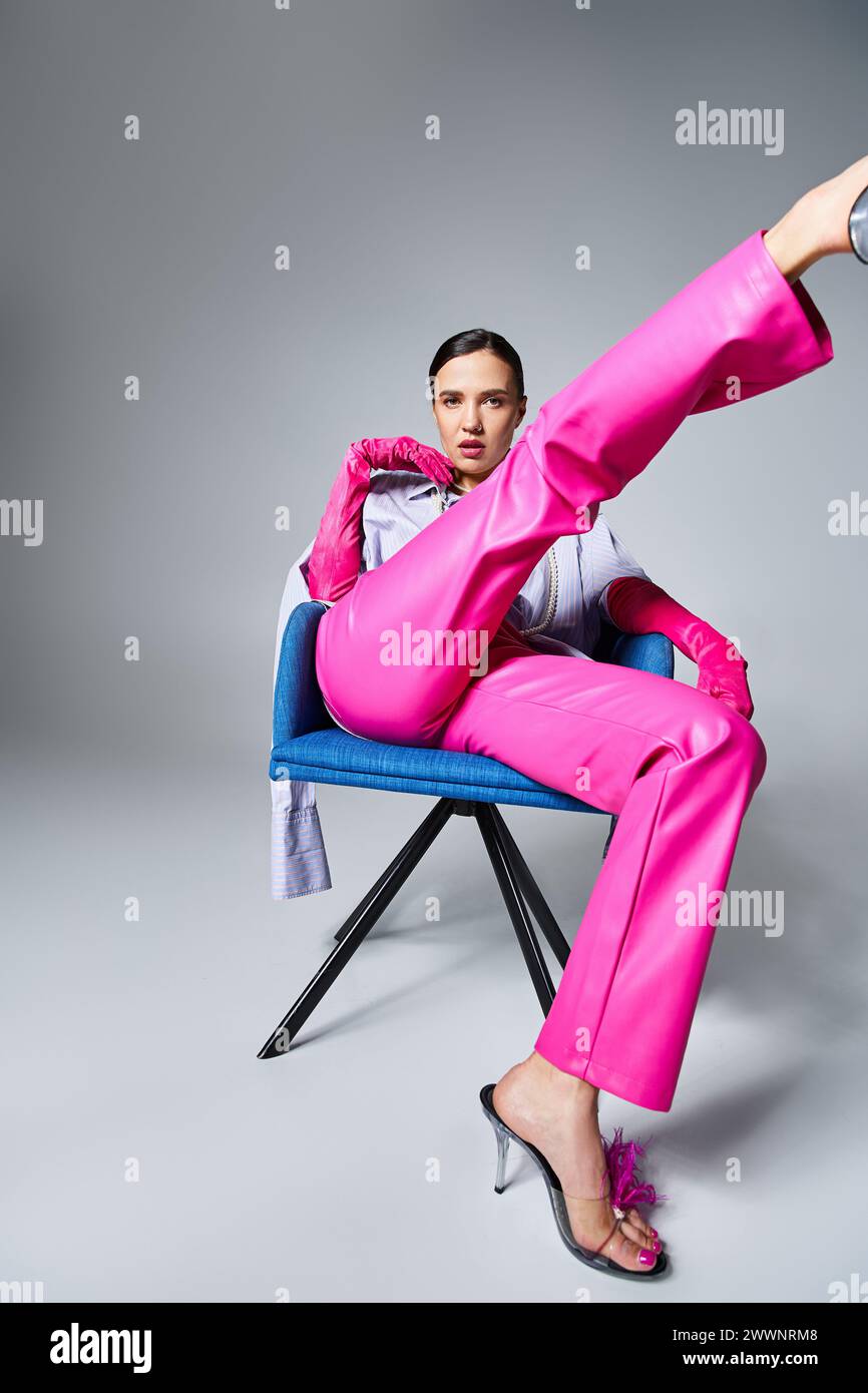 Confident brunette woman in trendy pink pants and shoes, sitting and kicking her leg up Stock Photo