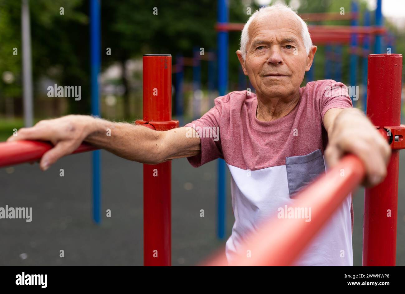 Old man standing between parallel bars outdoors Stock Photo - Alamy