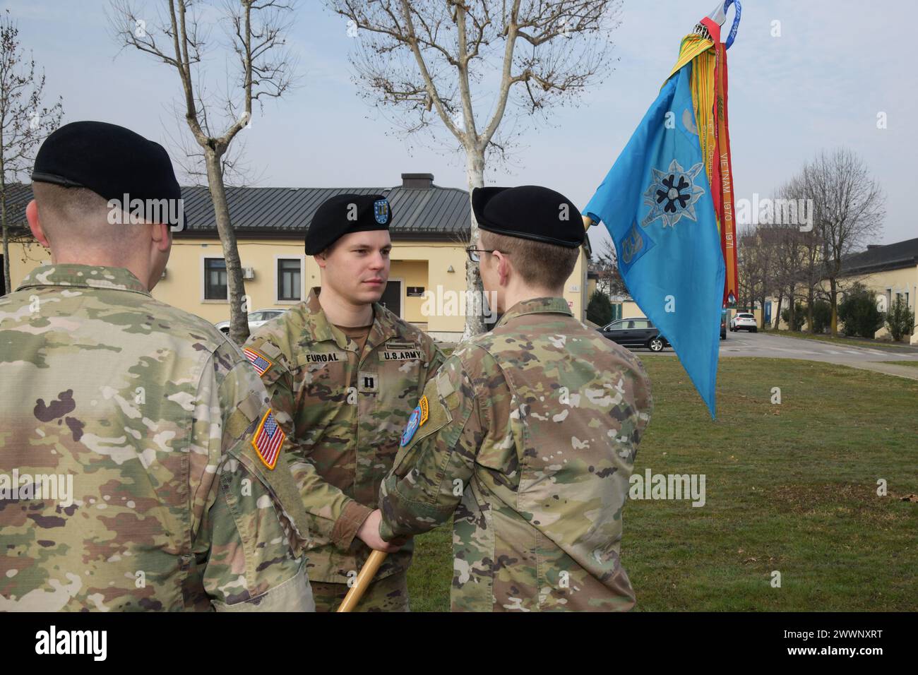 U.S. Army Capt. Erick T. Furgal, left, outgoing commander Bravo Company,  passes the guidon to Lt. Col. John G. Wildt, right, commander of 307th Military Intelligence Brigade, during the change of command ceremony for Bravo Company, 307th Military Intelligence at Caserma Ederle in Vicenza, Italy, Feb. 16, 2024.  Army Stock Photo