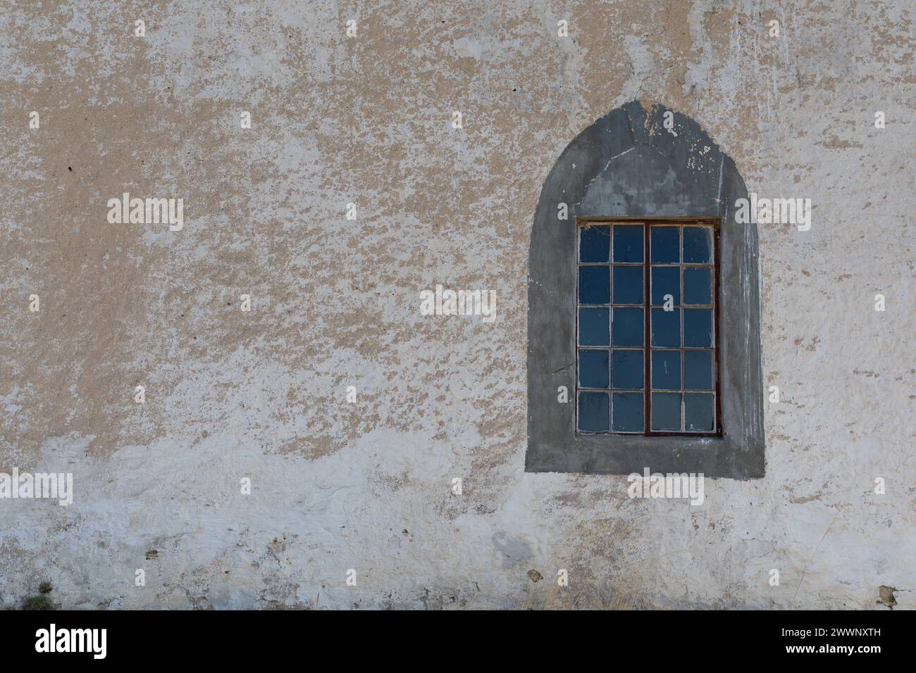 Gothic style window framed on right  of an old unused church building. On the left is peeling paint and also copy space. Stock Photo