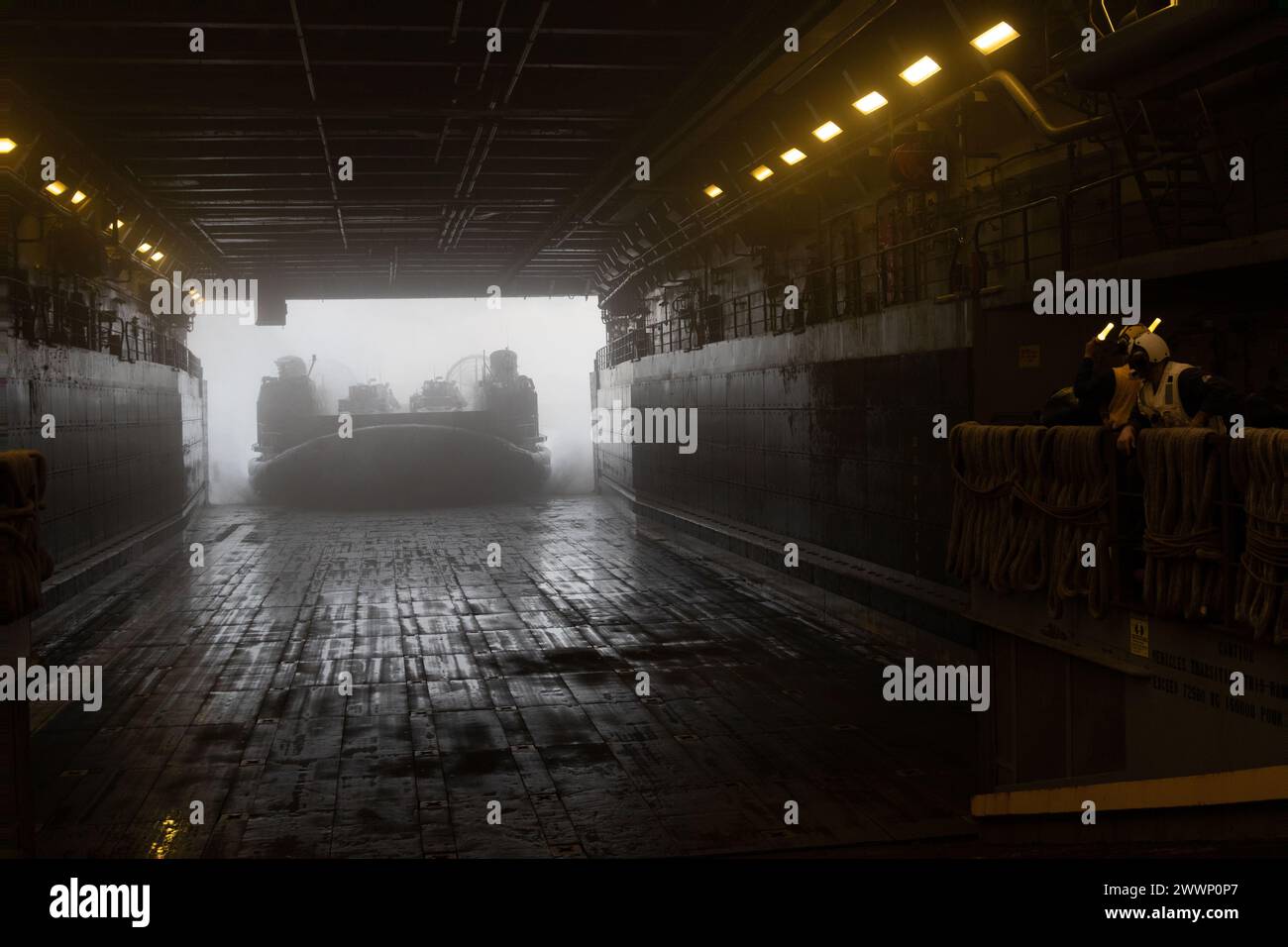 U.S. Navy Sailors with the amphibious dock landing ship USS Green Bay (LPD 20) guide a landing craft air cushion out of the well deck during a light armored vehicle reinforcement exercise, in the Philippine Sea, Feb. 14, 2024. The LAV reinforcement exercise tested Battalion Landing Team 1/1’s ship-to-shore capabilities to provide additional firepower and security while also offloading from the USS Green Bay. The 31st Marine Expeditionary Unit is operating aboard ships of the America Amphibious Ready Group in the 7th fleet area of operations to enhance interoperability with allies and partners Stock Photo