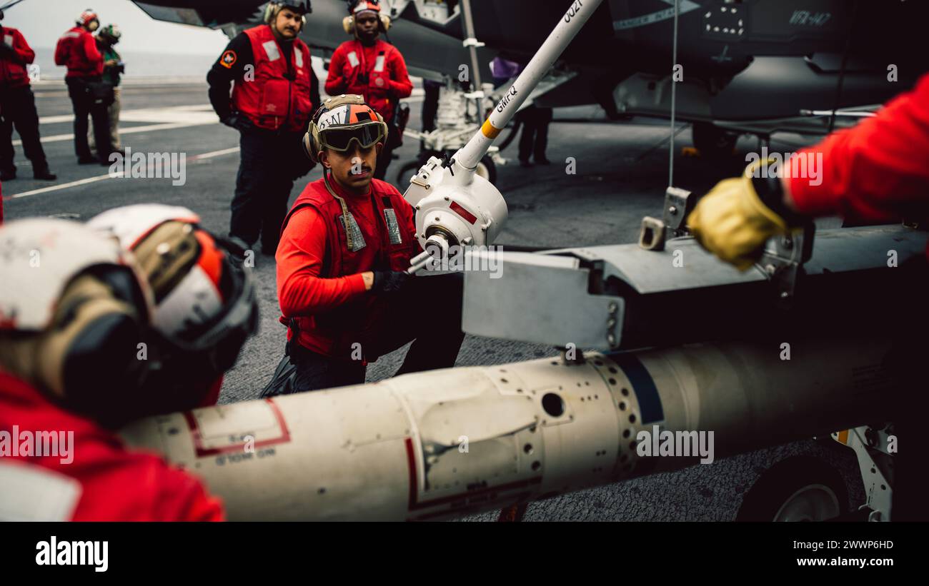 Aviation Ordnanceman 3rd Class Carlos Cordoba, from Bend, Oregon, assigned to Strike Fighter Squadron (VFA) 103 weapons department, lowers training ordnance onto a cart on the flight deck of Nimitz-class aircraft carrier USS George Washington (CVN 73) in the Atlantic Ocean, Feb. 16, 2024. George Washington is conducting Tailored Ships Training Availability and Final Evaluation Problem (TSTA/FEP). TSTA prepares the ship and crew for full integration into a carrier strike group through a wide range of mission critical operations.  Navy Stock Photo