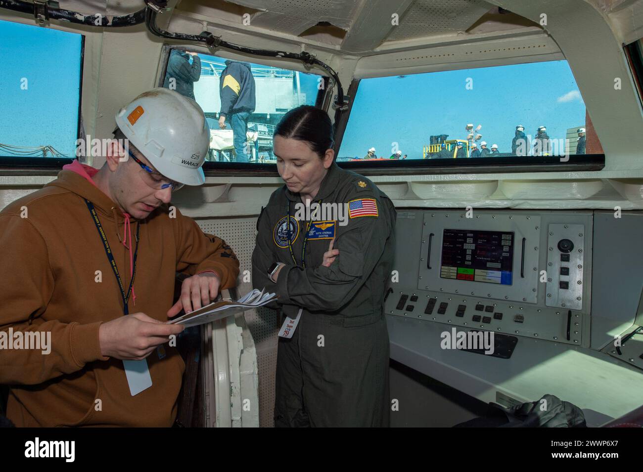 Newport News, V.A. (Feb. 14, 2024) – Lt. Cmdr. Katie Greiner discusses a checklist with an HII contractor in the Integrated Catapult Control System (ICCS) during the first “dead-load” testing of the electromagnetic aircraft launch system (EMALS). In this phase of testing, large, wheeled, car-like structures of graduated weights up to 80,000 pounds to simulate the weight of actual aircraft are launched off the carrier’s bow into the James River. John F. Kennedy is the second Ford-class aircraft carrier and is under construction at HII’s Newport News Shipbuilding (NNS) division in Newport News, Stock Photo