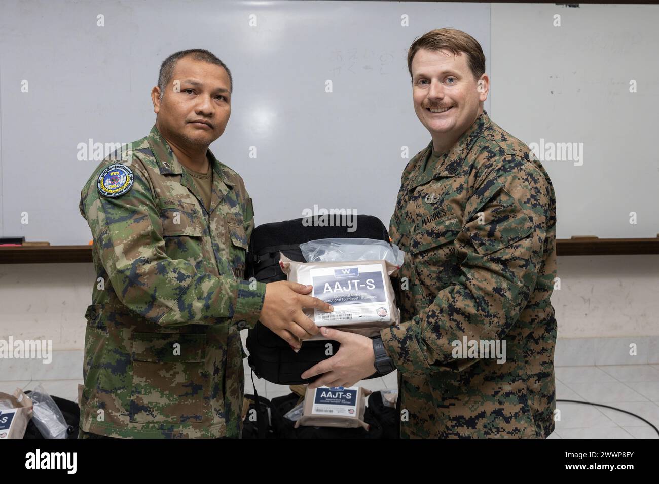U.S. Marine Corps Gunnery Sgt. Pierce Draper, right, the Humanitarian Mine Action (HMA) Thailand team leader with Explosive Ordnance Disposal (EOD) Company, 9th Engineer Support Battalion, 3rd Marine Logistics Group, presents medical supplies to Royal Thai Navy Chief Petty Officer 1st Class Pakawat Bangpoo, left, a medic with Humanitarian Mine Action Unit (HMAU) 2, Thailand Mine Action Center (TMAC), during a landmine casualty care (LCC) course graduation at Fort Bhanurangsi, Ratchaburi, Thailand, Feb. 2, 2024. Graduates of the LCC course received donations of medical equipment from the U.S. M Stock Photo