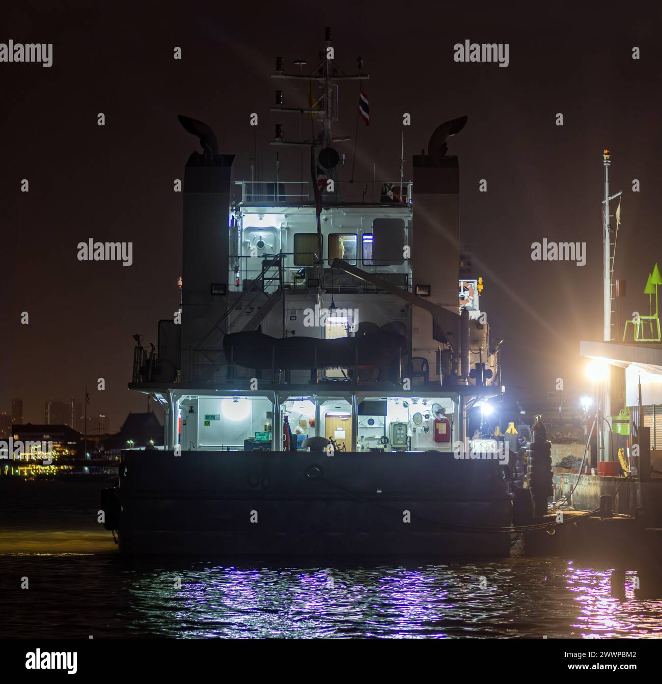 Tugboat moored at shore at night Stock Photo