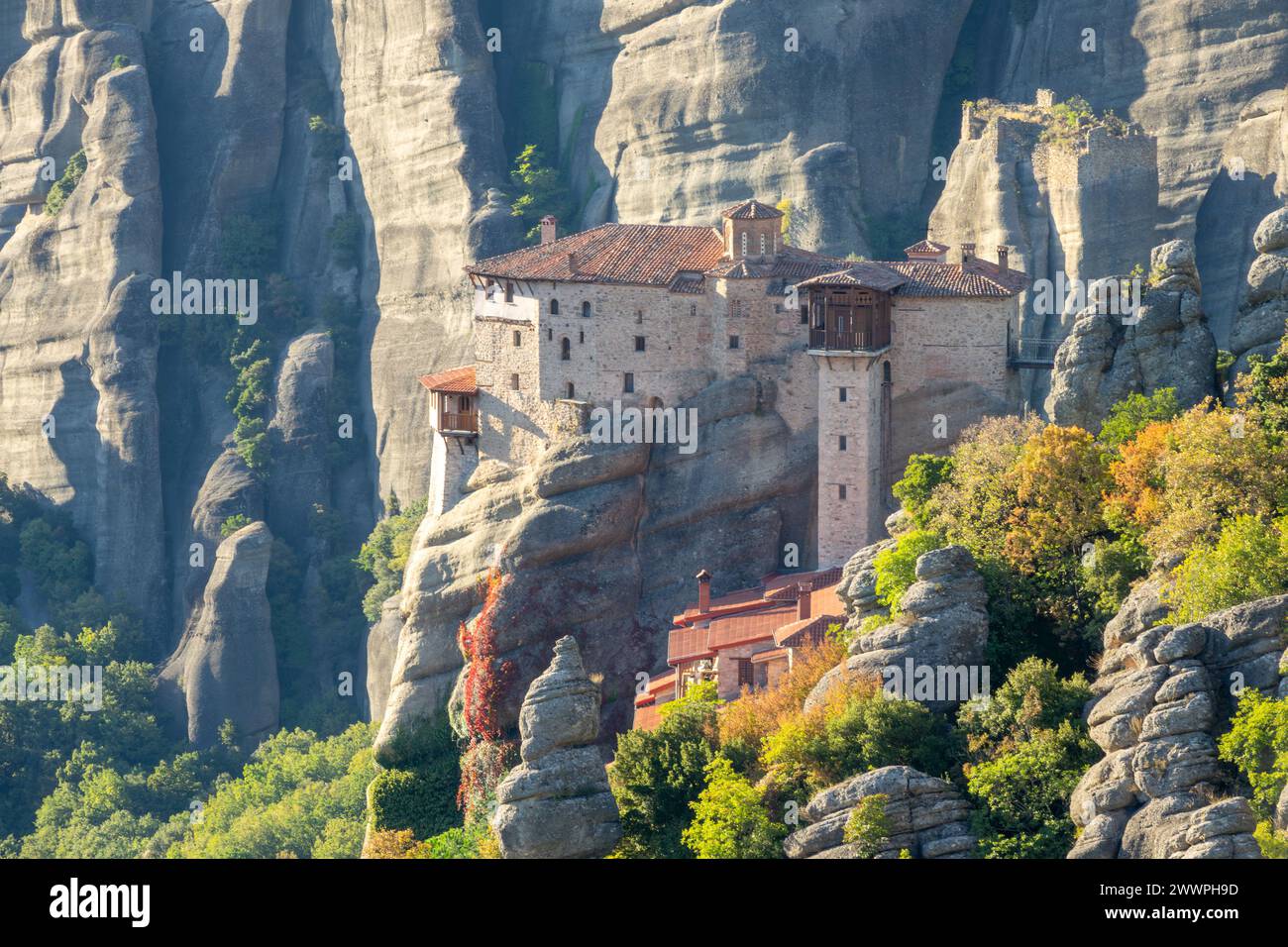 Greece. Sunny summer evening in the mountain valley of Meteora. Monastery on top of a cliff with a large mountain in the background Stock Photo