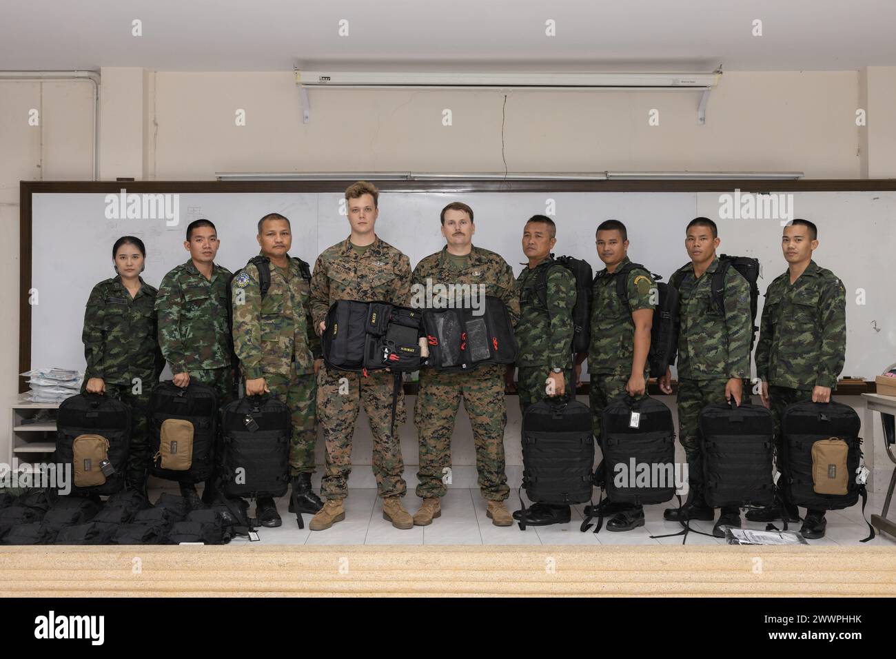 U.S. Marine Corps Gunnery Sgt. Pierce Draper, center right, the Humanitarian Mine Action (HMA) Thailand team leader with Explosive Ordnance Disposal (EOD) Company, 9th Engineer Support Battalion (ESB), 3rd Marine Logistics Group, and U.S. Navy Hospital Corpsman 2nd Class Jackson Hollund, center left, also with 9th ESB, pose for a photo with medical supplies during a landmine casualty care (LCC) course graduation at Fort Bhanurangsi, Ratchaburi, Thailand, Feb. 2, 2024. Graduates of the LCC course received donations of medical equipment from the U.S. Marine Corps Forces, Pacific HMA Program. Thi Stock Photo