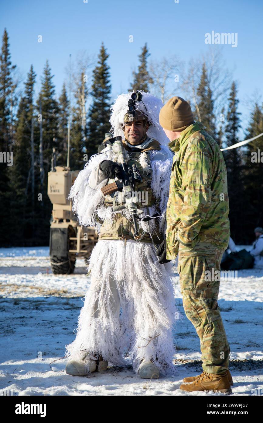 U.S. Army Staff Sgt. Rolando Bueno, gunnery sergeant, C Battery, 2nd Battalion, 8th Field Artillery Regiment, 1st Infantry Brigade Combat Team, 11th Airborne Division, speaks with an Australian officer about his experiences operating in the Alaskan winter during Joint Pacific Multinational Readiness Center 24-02 at Donnelly Training Area, Alaska, Feb. 16, 2024. The Large Scale Combat Operations scenario used in JPMRC 24-02 helps Soldiers and leaders develop and refine the tactics, techniques, and procedures necessary to successfully operate in remote and extreme Arctic winter conditions and ov Stock Photo