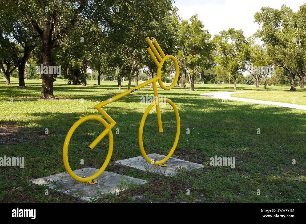 A yellow bicycle sculpture on concrete block in park Stock Photo