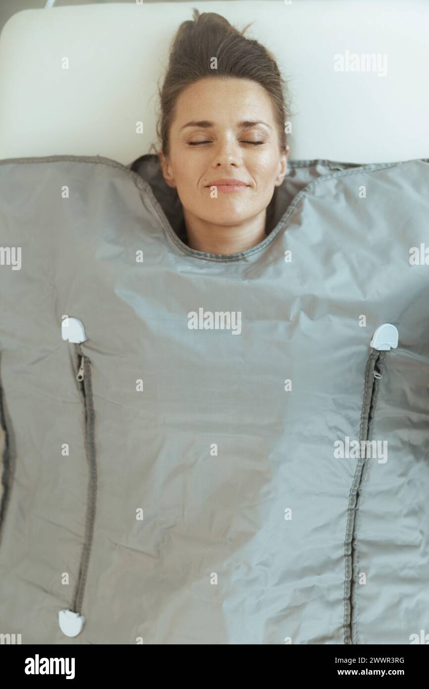 Healthcare time. relaxed modern woman in massage doing whiskey swaddling procedure in