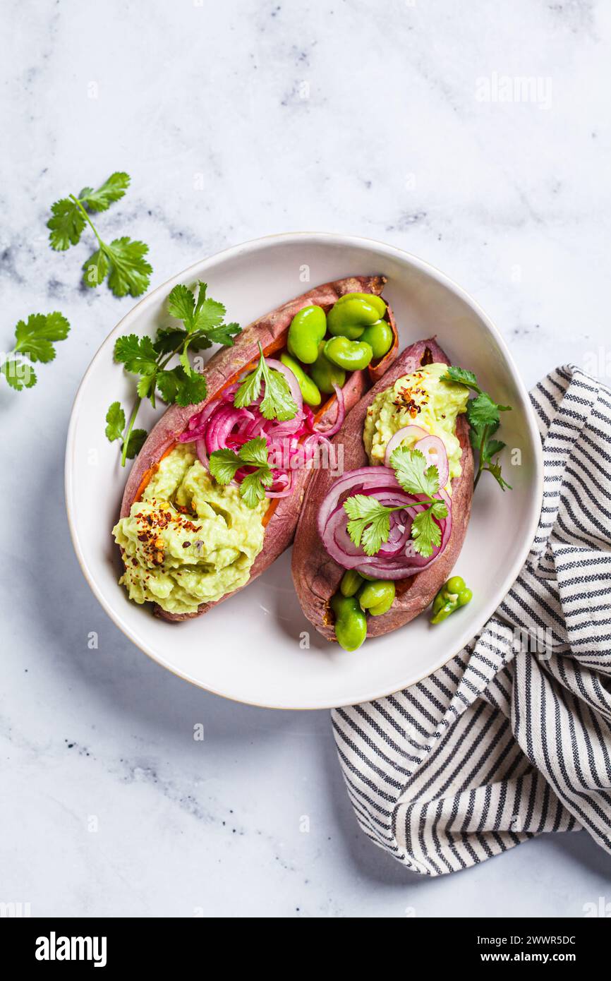 Baked sweet potato halves with guacamole, edamame beans, pickled red