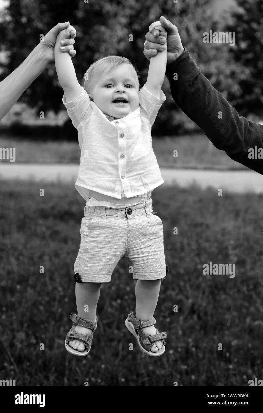 Father and mother parents holding child baby hands. Cute little baby on ...