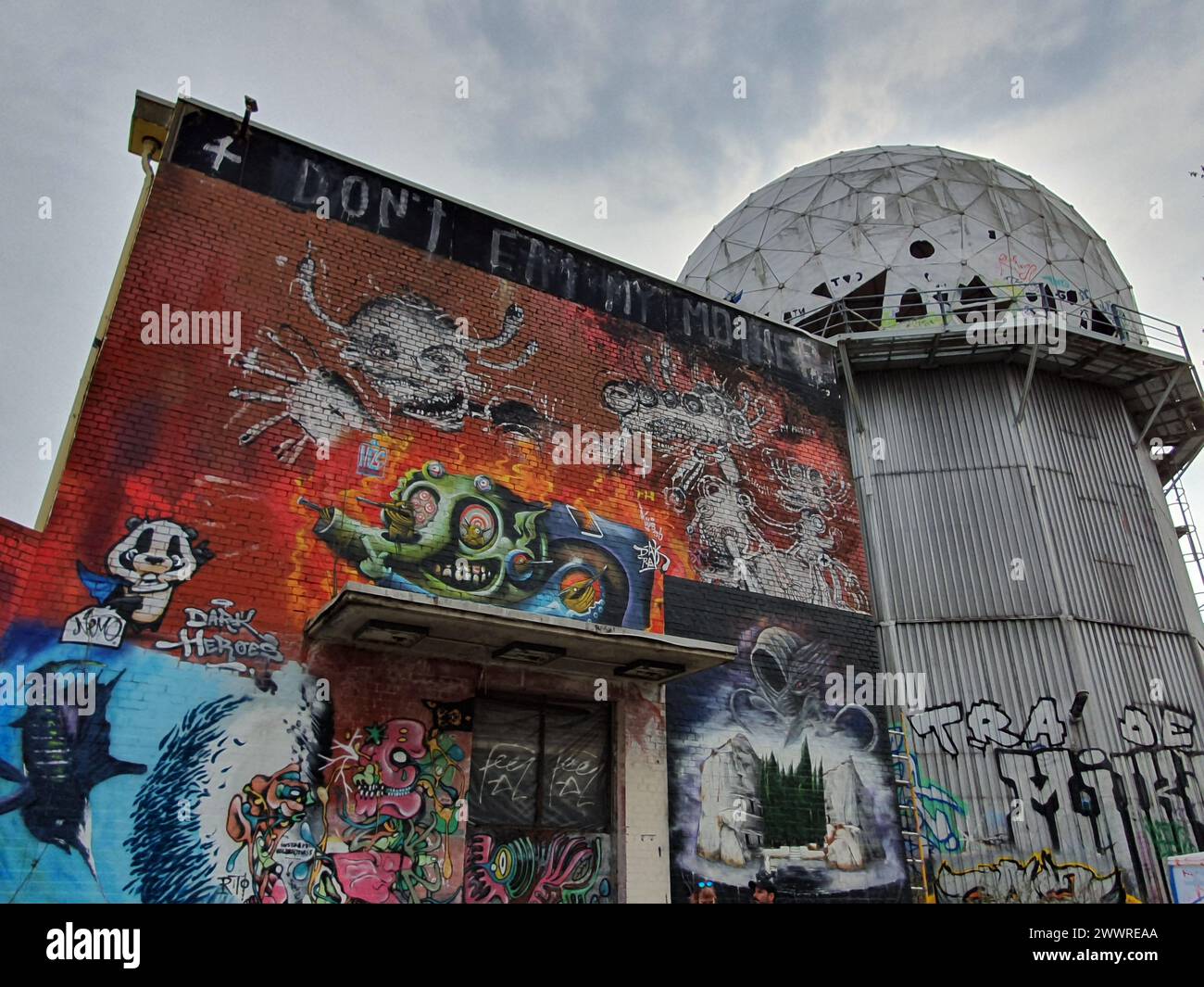 Graffiti-covered building beside a tall urban structure Stock Photo