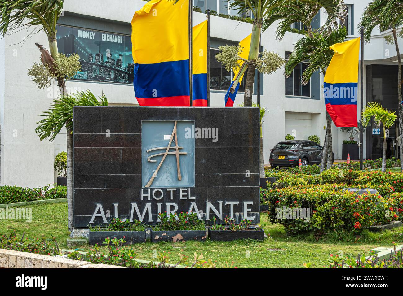 Cartagena, Colombia - July 25, 2023: Central Bocagrande Carrera 2. Hotel Almirante entrance and large sign in garden with natiional flags, red flowers Stock Photo