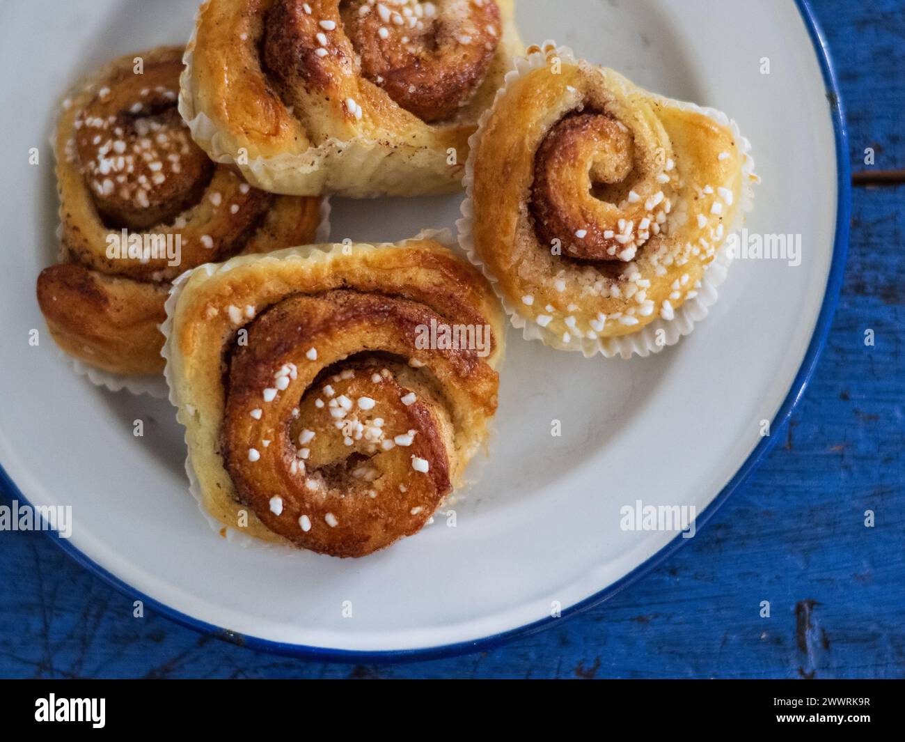 Cinnamon buns on white plate on blue table Stock Photo