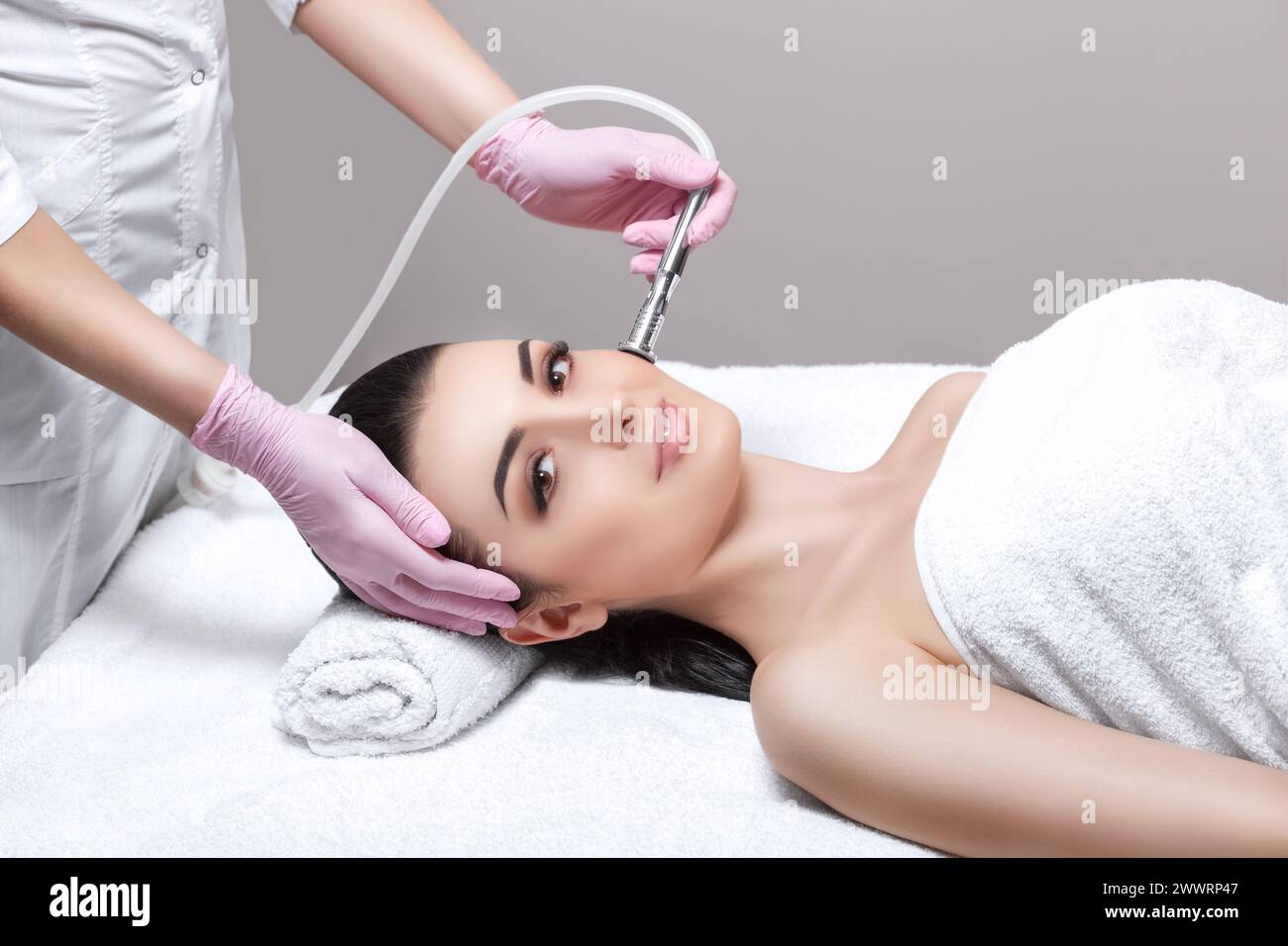 The cosmetologist makes the procedure Microdermabrasion of the facial skin of a beautiful, young woman in a beauty salon.Cosmetology and professional Stock Photo