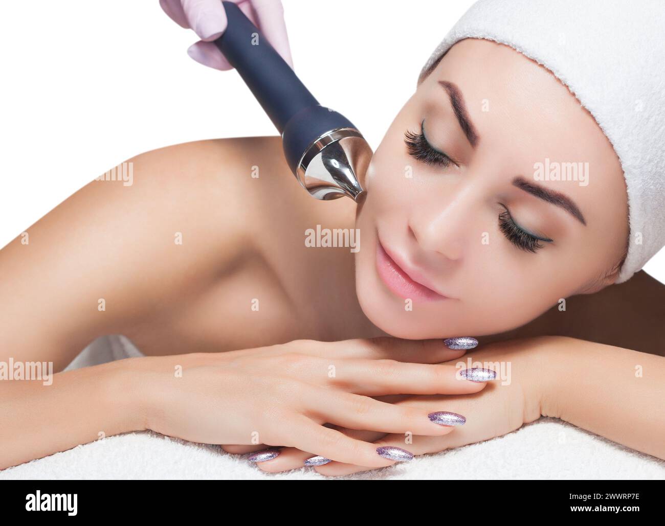 The cosmetologist makes the procedure an ultrasonic cleaning of the facial skin of a beautiful, young woman in a beauty salon.Cosmetology and professi Stock Photo