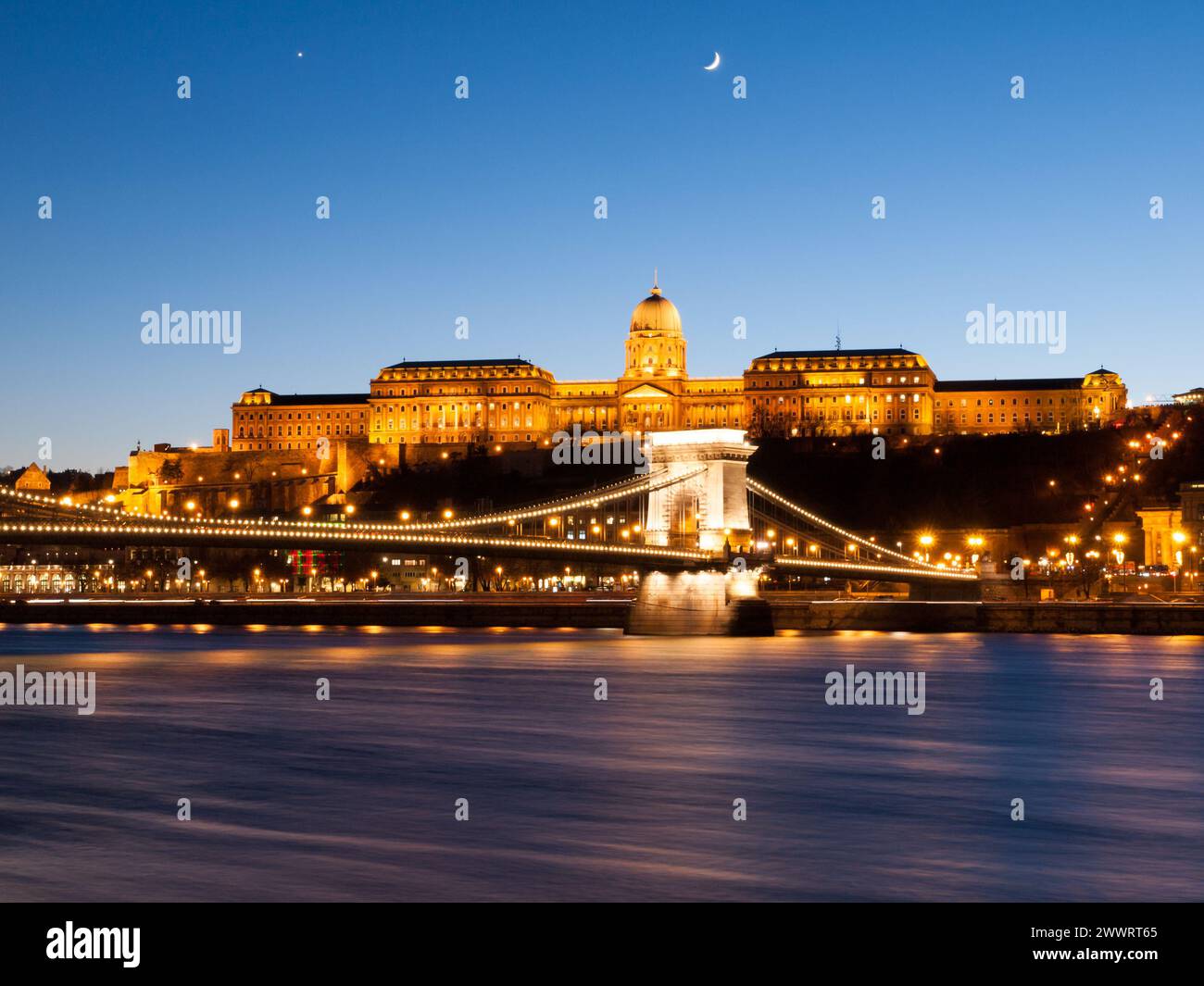 Illuminated Buda Castle and Chain Bridge over Danube River in Budapest by night, Hungary, Europe. UNESCO World Heritage Site. Long exposure shot with blurred water stream. Stock Photo