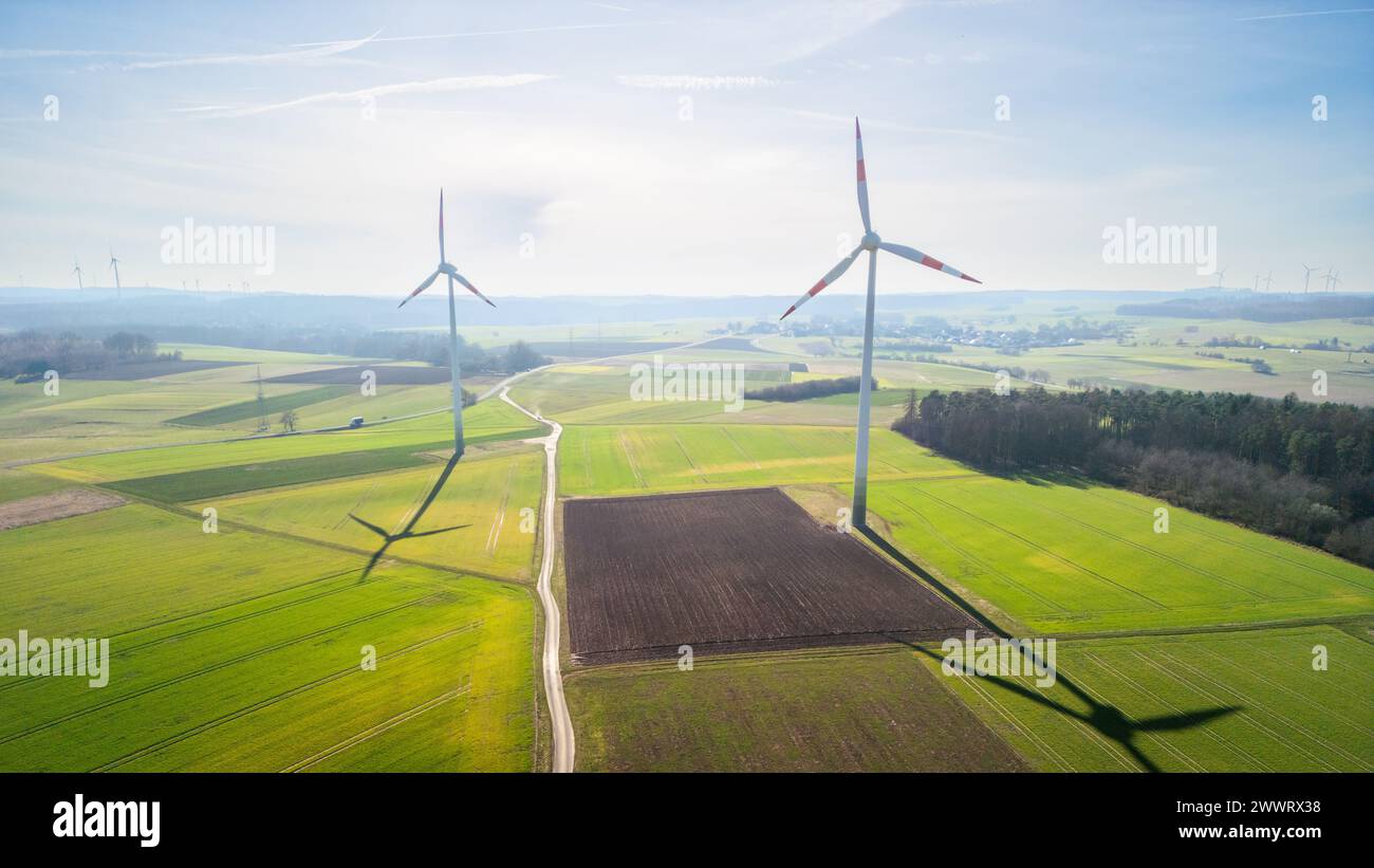 Wind turbines and power lines in a lush green field Stock Photo - Alamy