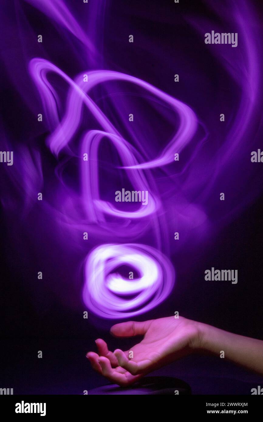 A long exposure shot of a hand playing with a glowing light Stock Photo